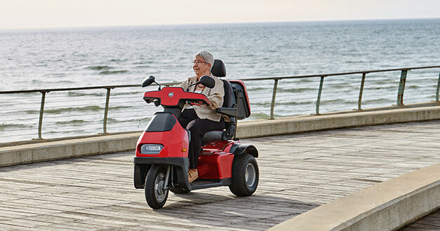 AFIKIM Red Afiscooter S3 Outdoor Mobility Scooter with Rider on Cemented Surface by the Seaside