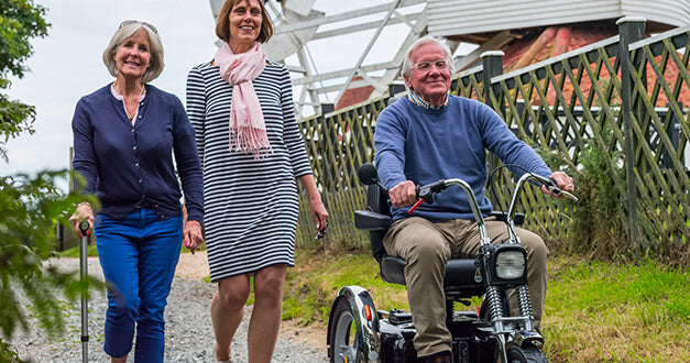 AFIKIM Silver Afiscooter SE Mobility Scooter With Rider Outdoor With Companion On Rough Road Surface