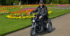 AFIKIM Silver Afiscooter SE Mobility Scooter With Rider And Rear Tray Outdoor In The Park View