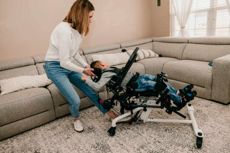 Altimate Medical EasyStand Bantam Small Stander With User Assisted By Mother During Sit To Stand Transition