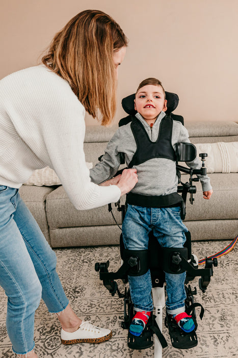 Altimate Medical EasyStand Bantam Small Stander In Use With Child Standing And Receiving Assistance From Mother