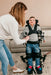 Altimate Medical EasyStand Bantam Small Stander In Use With Child Standing And Receiving Assistance From Mother