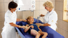 Arjo Concerto And Basic Shower Trolley Pediatric User With Carers Assisting During A Bathing Session