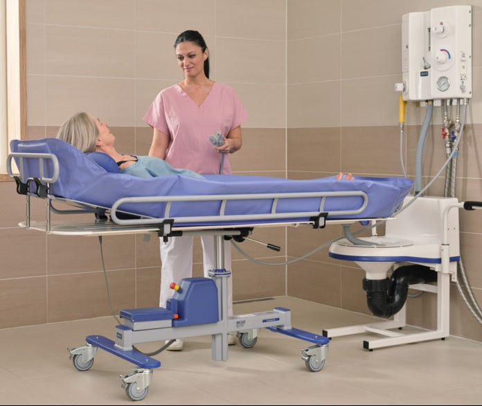 Arjo Concerto And Basic Shower Trolley With Patient And Caregiver Demonstrating Safe Head Support