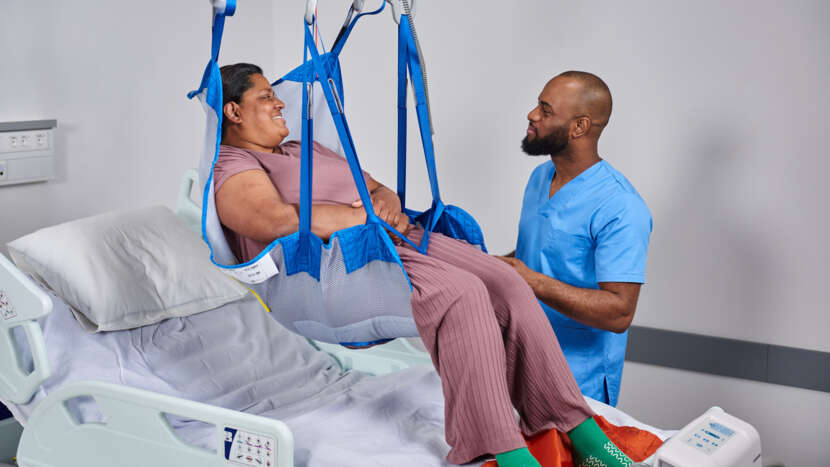 Arjo Loop Hammock Sling Six Strap Attachment Design With Caregiver For Patient Handling