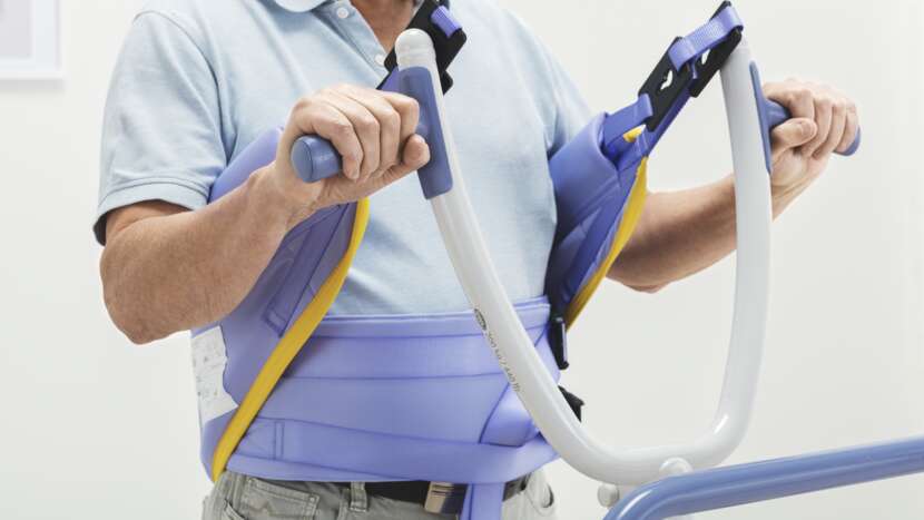 Arjo Sara Flex Sit to Stand Lift With Patient Holding Handlebar View