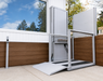Atlas Nano Vertical Platform Lift Installed On An Outdoor Patio Enclosed With Clear Glass Panels And Equipped With An Access Ramp.