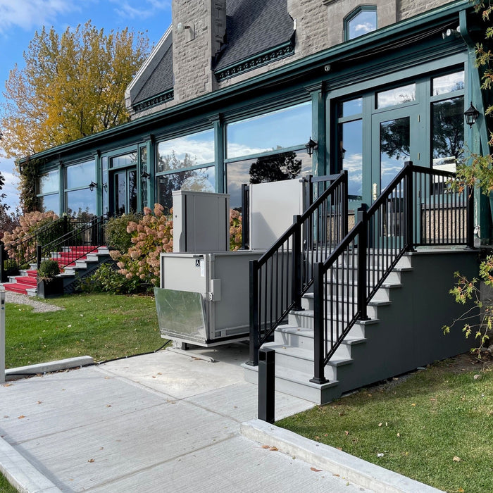 Atlas VISTA Vertical Platform Lift Providing Accessible Entry Onto A Raised Wooden Porch Deck.