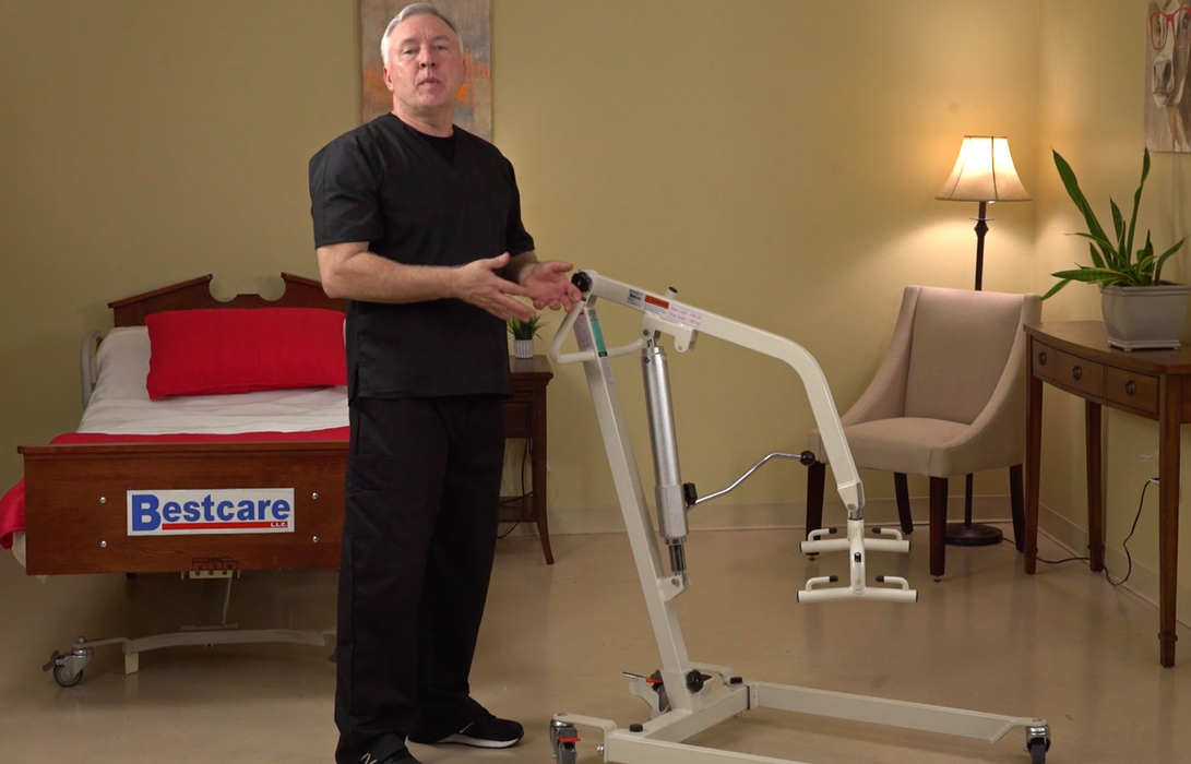 Bestcare BestLift PL400HE Hydraulic Electric Full Body Lift With Caregiver Standing Next To PL400HE Lift