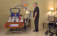 BestLift ProCare PL500 Ergonomic Patient Lift With Caregiver Holding Hand Control And Patient Transferred To Bed