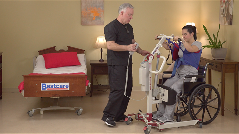 Bestcare BestStand SA400HE Mini Electric Sit-to-Stand Lift With Caregiver And Patient In Wheelchair Transfer