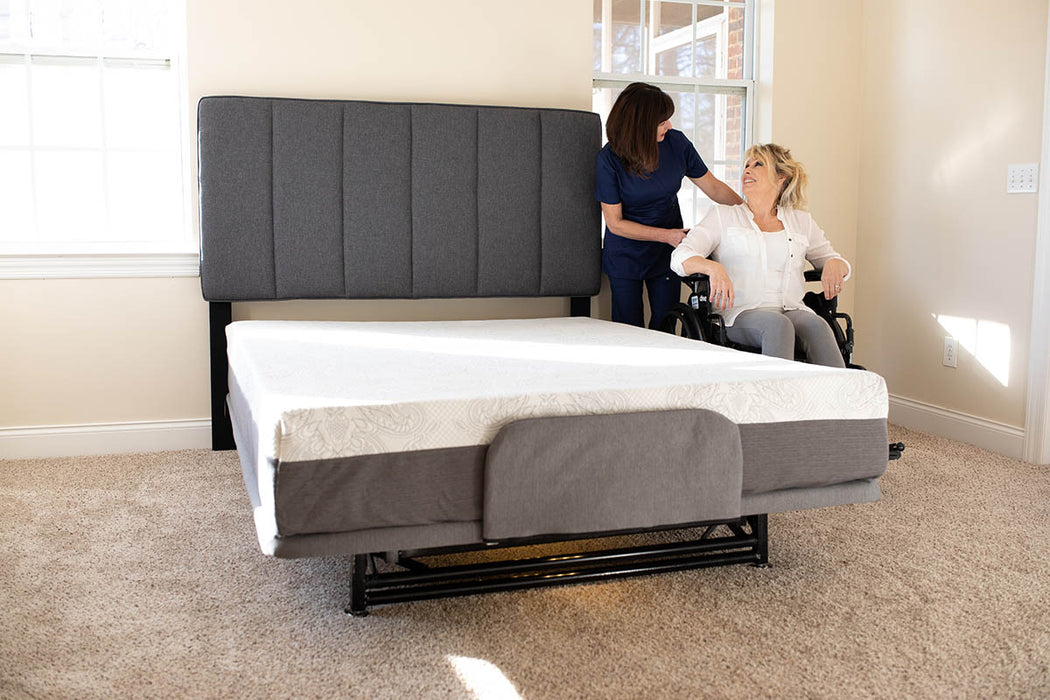 Flex A Bed Hi Low Adjustable Bed In Low Fully Flat Position With Mattress Pillow Headboard And User In Wheelchair Front Lower View