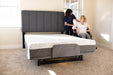 Flex A Bed Hi Low Adjustable Bed In Low Fully Flat Position With Mattress Pillow Headboard And User In Wheelchair Front Lower View