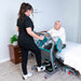 Handicare Mover Plus Sit-to-Stand Platform For Safe Indoor Mobility And Caregiver Support With Up To 330 Lb Capacity In Use By A Patient With Assist