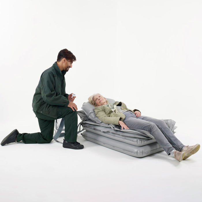 Joerns Mangar Camel Lifting Cushion With Patient Lying Down Assisted By Caregiver And Airflo 24 Decompressor View