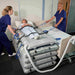 Joerns Mangar Rhino Lifting Device And Mangar Swift Used In Bed Transfer With Patient Assisted By Caregiver View