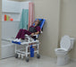 MJM International All Purpose Dual Shower Transfer Chair With Tilt Slider In Bathroom Setting With Patient In Reclined Head And Knee Raised Position View