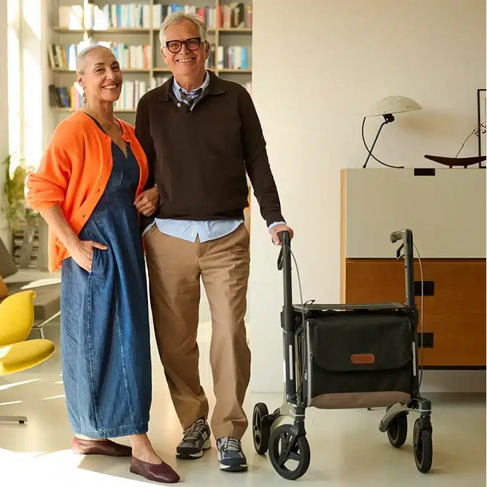 Rollz Air Carbon Rollator In Mint Green Being Easily Carried And Lifted By A User Indoors.