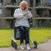 Rollz Air Carbon Rollator In Mint Green With A User Comfortably Seated On It.