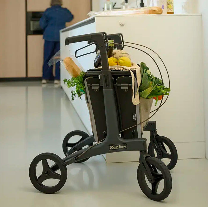 Rollz Flow Aluminum Walker In Granite Black Showing The Spacious Storage Underseat Bag Filled With Groceries.
