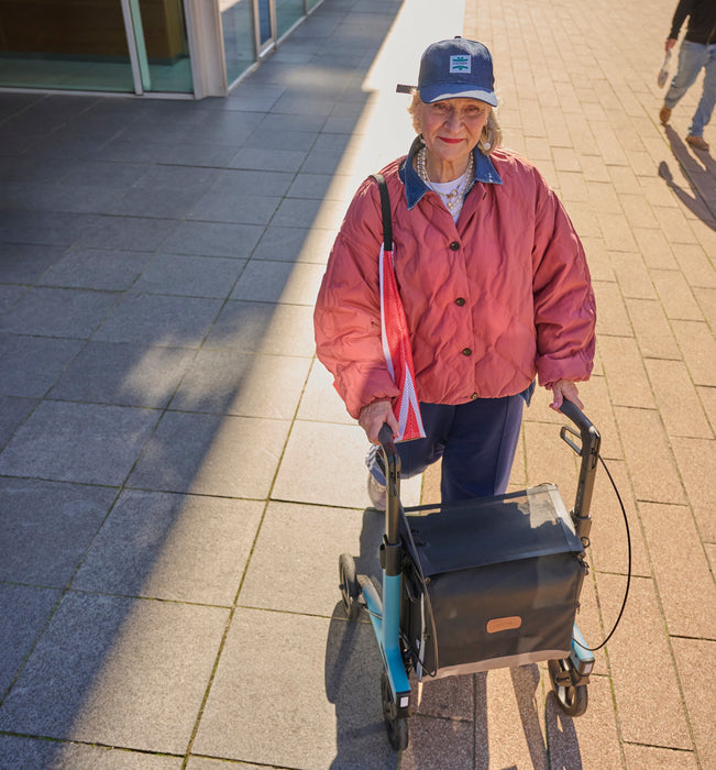 Rollz Flow Aluminum Walker In Granite Black Top Down Front View Of A User Walking Behind The Device.