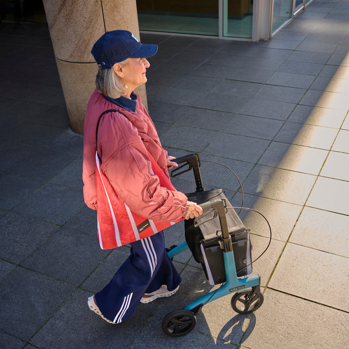 Rollz Flow Aluminum Walker In Granite Black Top Down View Of A User Walking Behind The Device.