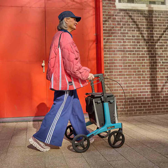 Rollz Flow Aluminum Walker In Granite Black Being Used By A Person Walking Outdoors.
