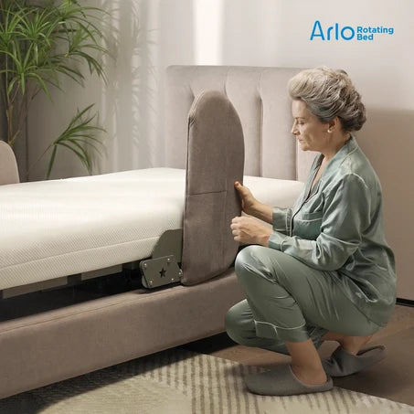 A woman in sage green pajamas kneels beside a bed with the Starsleep Orin Arlo Rotating Bed, demonstrating the side support panel that allows the mattress to tilt. The brand logo 'Arlo Rotating Bed' is visible in the top right corner.