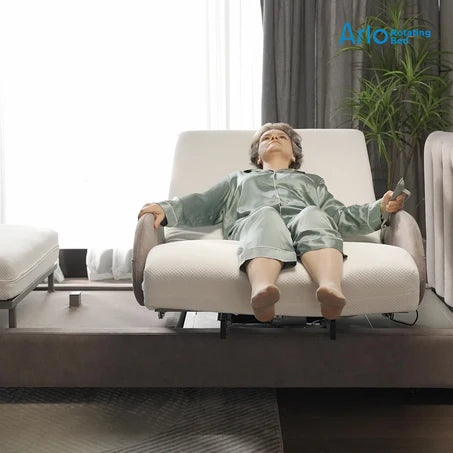 A mannequin dressed in a light green pajama set reclining on a Starsleep Orin Arlo ergonomic rotating chair bed with a remote control, set in a modern living room environment with a window, curtains, and a plant.