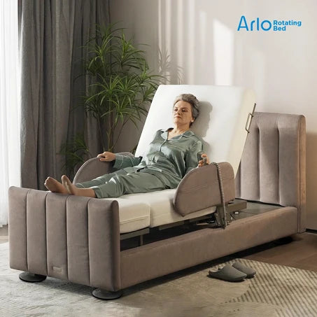 A woman in a green pajama set reclines on a Starsleep Orin Arlo ergonomic rotating chair bed with a padded headrest, side rails, and upholstered base, shown in a softly lit bedroom. The Arlo Rotating Bed logo appears in the top right corner.