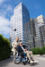 Strongback Mobility Comfort: 24+AB Wheelchair Lightweight, Ergonomic Design for Superior Comfort and Control, Modern architecture and bright, clear sky smilling elderly couple outdoors.